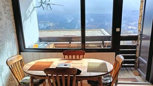 Ein Essbereich mit einem großen Fenster und Blick auf eine Berglandschaft.