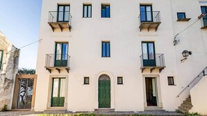 A multi-story building with balconies, a central entrance, and a staircase on the right. - Pietra del Bagno - Exclusive sea-view residence (Lipari)