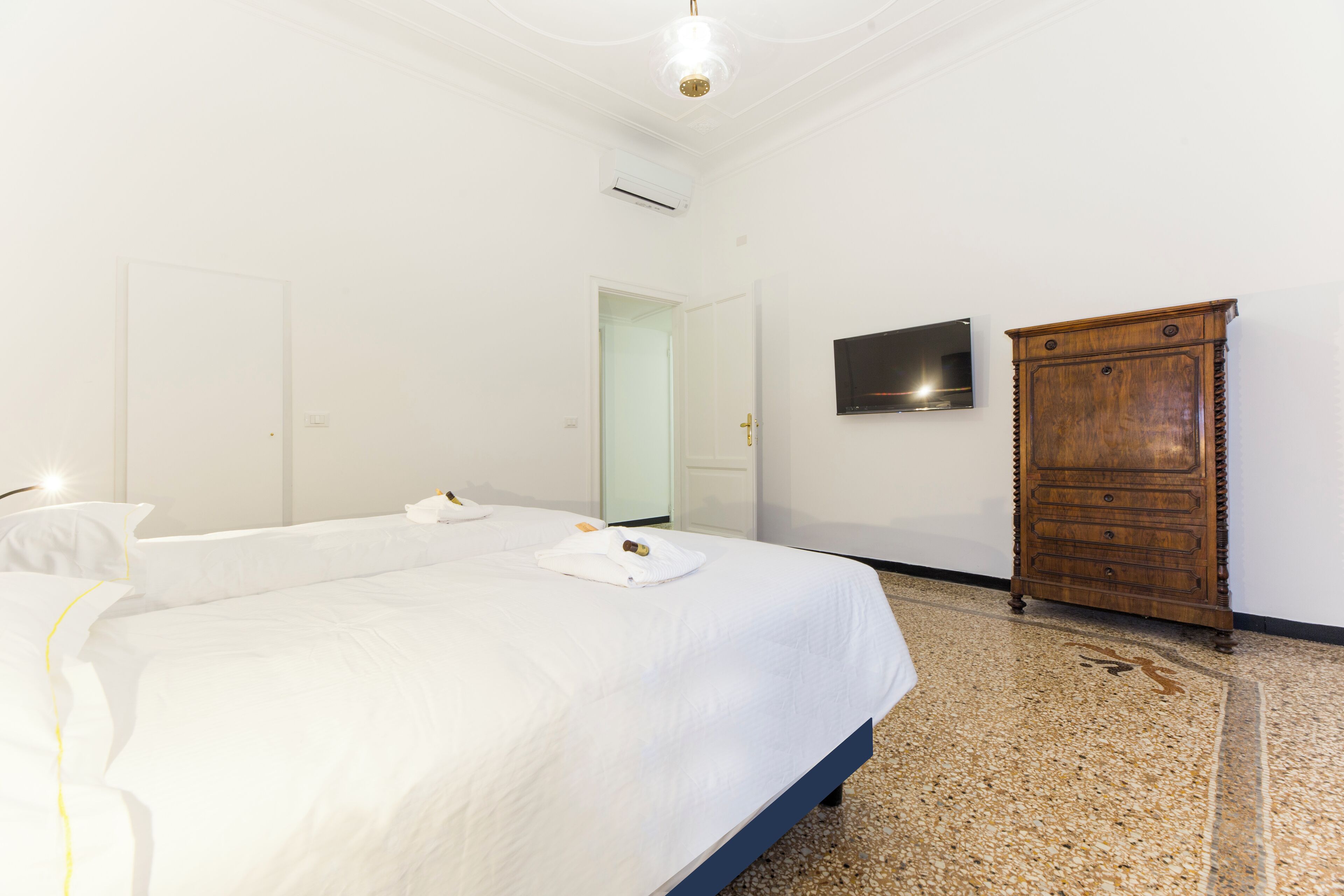 Une chambre d’hôtel avec deux lits, une armoire en bois, un téléviseur à écran plat et un luminaire au plafond.