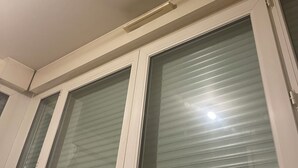 Ein Zimmer mit Deckenlüfter, einem Fenster mit Jalousien und einer Tür mit Griff.