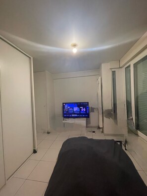 Une chambre à coucher avec un lit, un téléviseur fixé au mur et un luminaire au plafond.