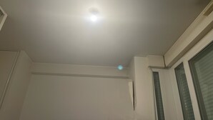 Ein Zimmer mit einer eingelassenen Deckenleuchte, einem Fenster mit Jalousien und einer Tür.