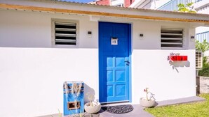 A building with a blue door, a mailbox, and a small garden area with plants. - La Rose Bleue - Your renovated cocoon a stone's throw from Le Diamant beach (Le Diamant)