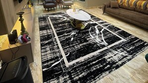 Ein modernes Wohnzimmer mit einem schwarz-weißen Teppich, einem runden Couchtisch und einem braunen Sofa.