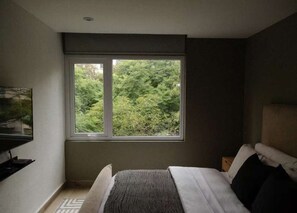 A bedroom with a large window, a bed, a TV, and a small desk. - HOM Elba Retreat Trendy 2 BR in Mexico City (Mexico City)
