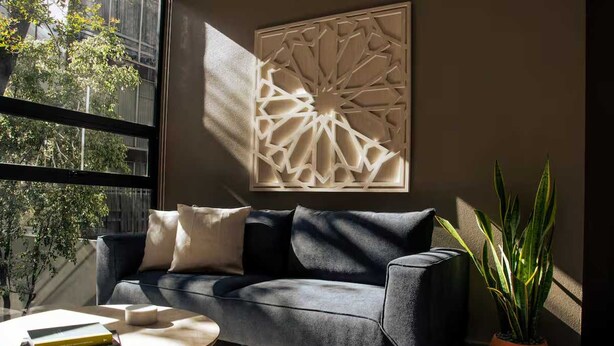 Ein modernes Wohnzimmer mit einem dunkelgrauen Sofa, einem runden Couchtisch und einer dekorativen Wandverkleidung.
