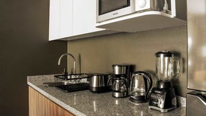Eine Küche mit Mikrowelle, Kaffeemaschine, Mixer und Wasserkocher auf der Arbeitsfläche.