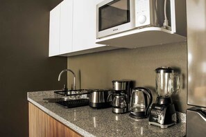 A kitchen with a microwave, coffee maker, blender, and kettle on the counter. - HOM Mineria Expanse Modern 2 BR in Mexico (Mexico City)