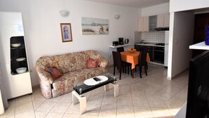 Espaço compacto com sofá, mesa de jantar e cozinha compacta.