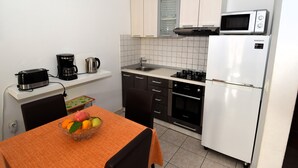 Uma cozinha compacta com micro-ondas, cafeteira e geladeira.