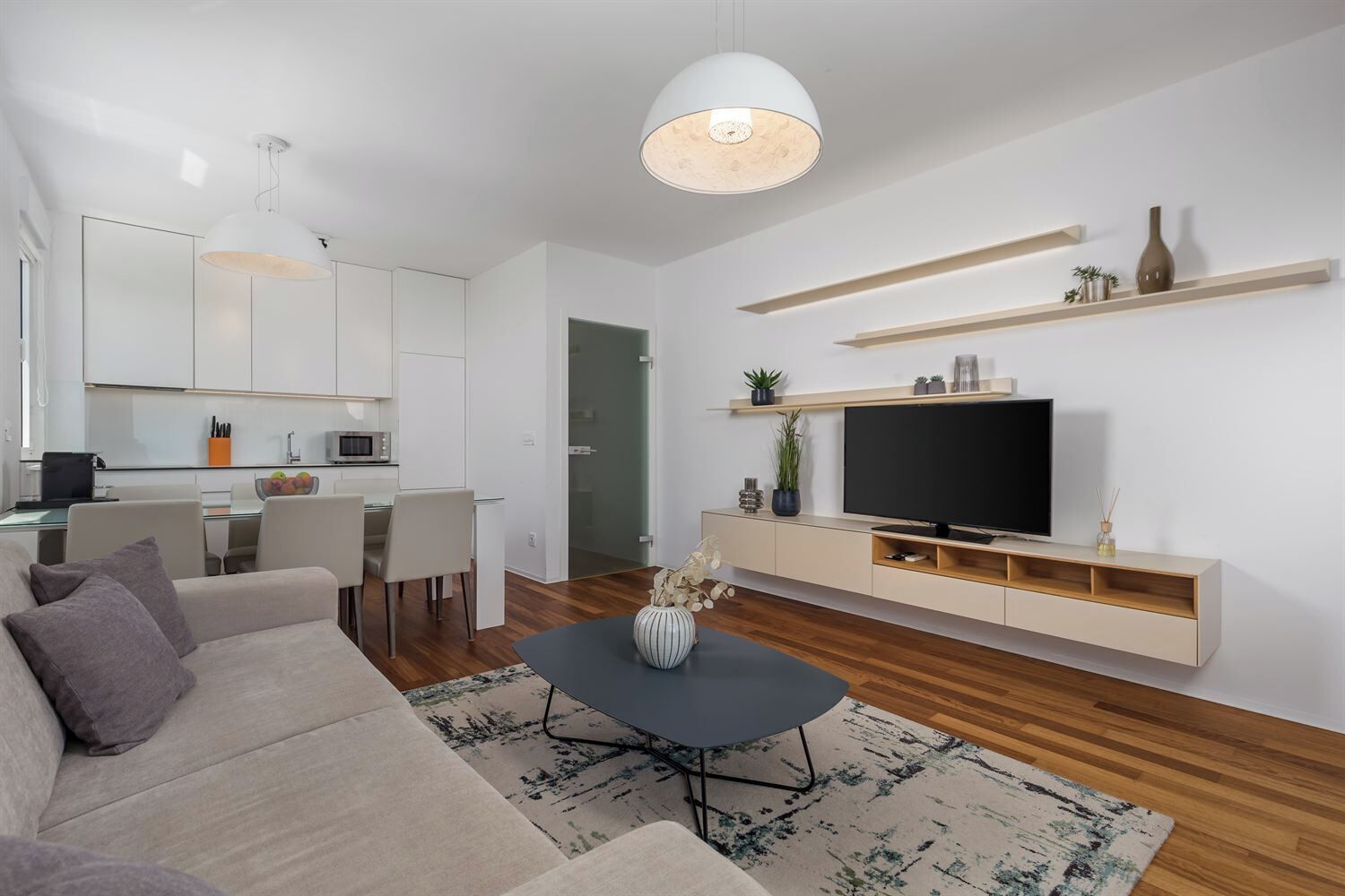 A modern living room with a sofa, coffee table, TV, and minimalist decor.
