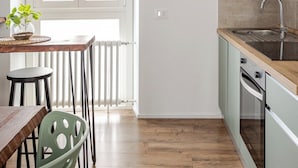 A modern kitchen with a wooden countertop, a built-in oven, and a window with white blinds. - Piermarini Suite in the historical center of Monza- 15 min from Milan (Monza)