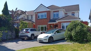 A residential area with two parked cars, a brick house, and a well-maintained lawn. - Room-calm and Warm Place Near to the tow (Cavan)