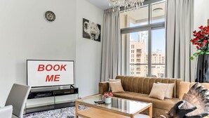 Una sala de estar moderna con un sofá, una mesa de centro y un televisor que muestra “BOOK ME”.