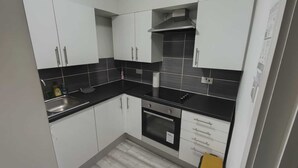 Uma cozinha com armários brancos, bancadas pretas, exaustor de aço inoxidável e forno embutido.