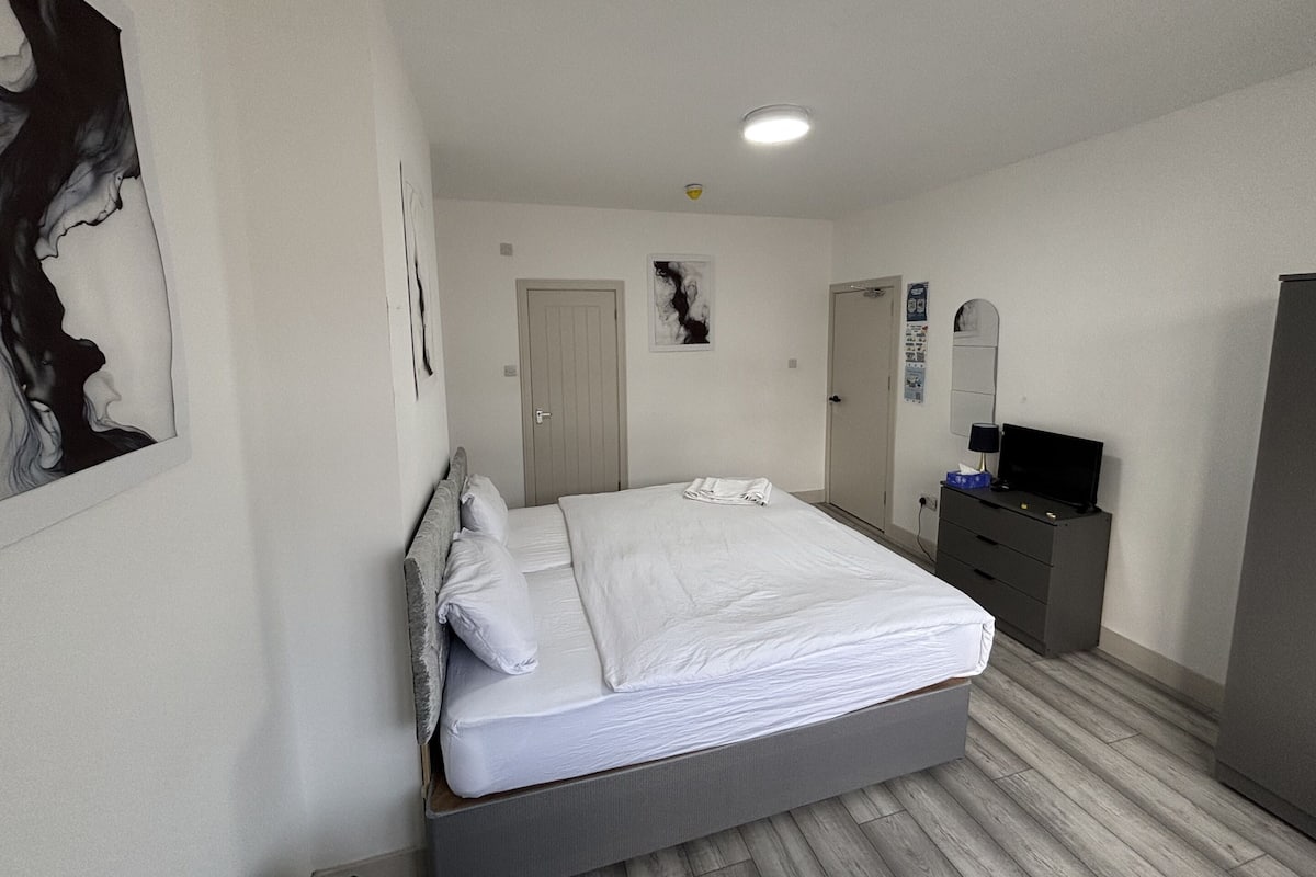 A modern bedroom with a bed, dresser, and a television.