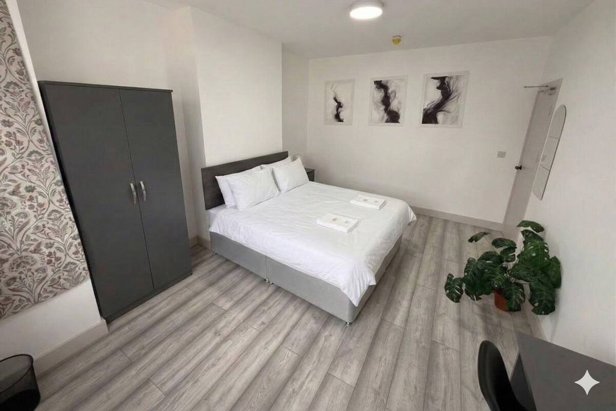 A modern bedroom with a bed, wardrobe, and artwork on the wall.