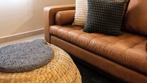 Eine braune Ledersofa mit drei strukturierten Kissen in verschiedenen Farbtönen.