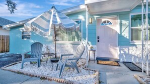 A house with a number 5025, a porch with two chairs, a striped umbrella, and a welcome mat. - Family Home 10 Mins to Beach Pets Welcome (Gulfport)