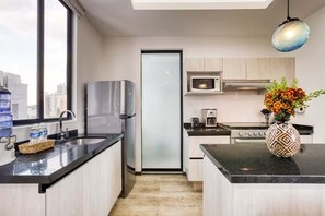 A modern kitchen with a refrigerator, microwave, and stove. There is a window with a view of buildings outside. - HOM Roma l Unique 1 BR in Mexico City (Mexico City)