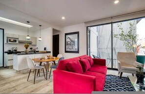 A modern apartment with a dining area, a red sofa, and a large window offering a view of the city. - HOM Roma l Unique 1 BR in Mexico City (Mexico City)