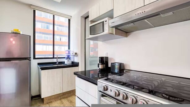 A modern kitchen with a stainless steel refrigerator, a gas stove, a microwave, and a coffee maker. - HOM Roma Double l Spacious 2 Bedroom in Mexico City (Mexico City)