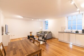 Um apartamento moderno com área de jantar, sofá, cozinha com janela e TV de tela plana.