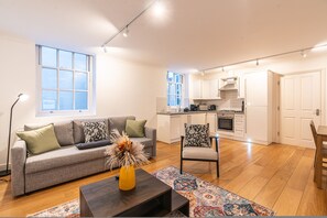 Um apartamento moderno com sala de estar, sofá, mesa de centro e cozinha.