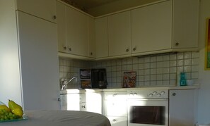 A kitchen with white cabinets, a coffee maker, and a small oven. - Apartment 'Findus' with Private Terrace and Wi-Fi (Kempten-Haldenwang)
