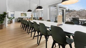 A spacious dining area with a long table and multiple chairs, large pendant lights, and a view of the outdoors. - 5 Star Holiday Home in Glesborg (Glesborg)