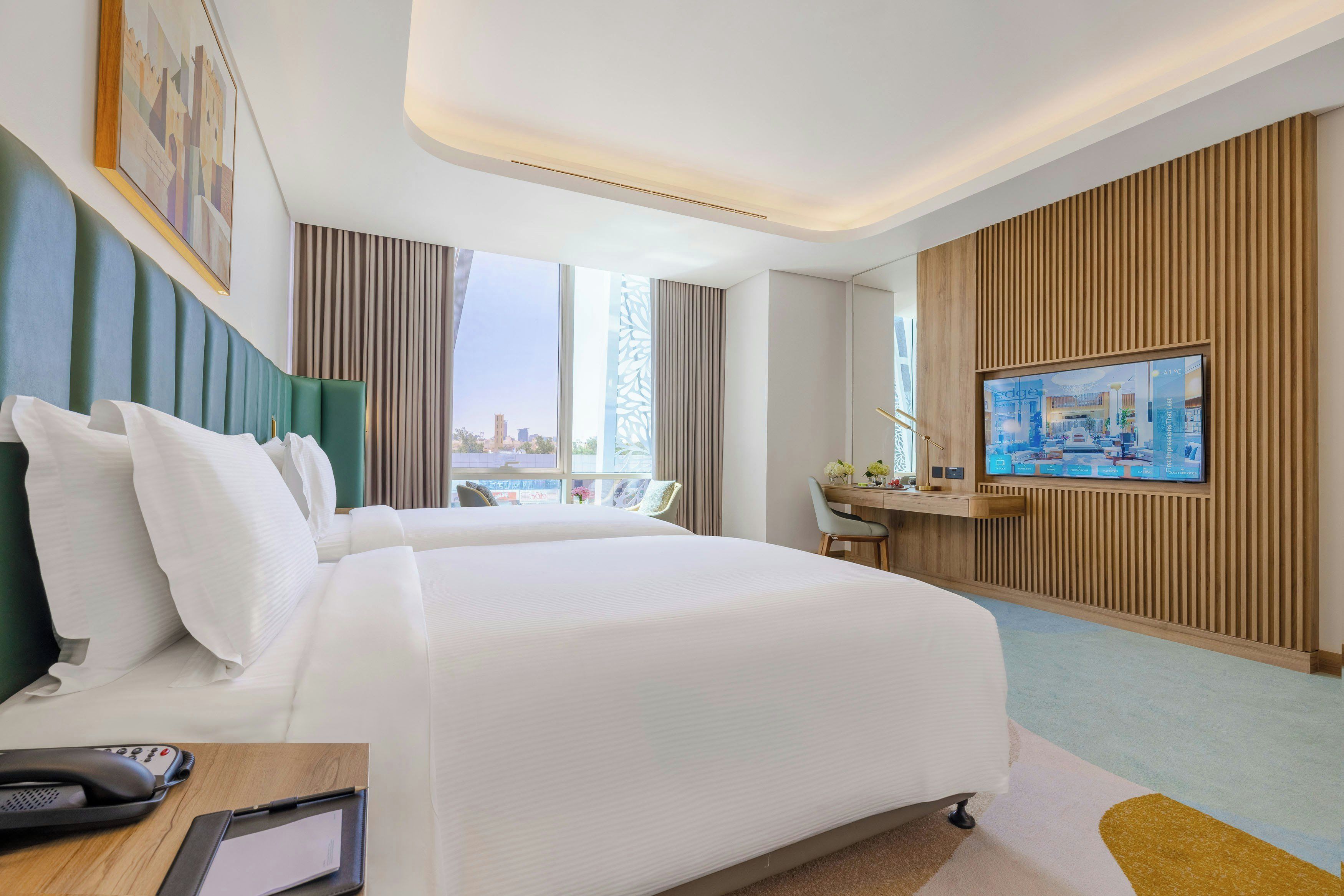 Habitación de hotel con una cama grande, un escritorio, una televisión y vistas a la ciudad.