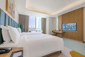 A hotel room with a large bed, a desk, a television, and a view of the city. - Edge Riyadh Al Rabie (Riyadh)