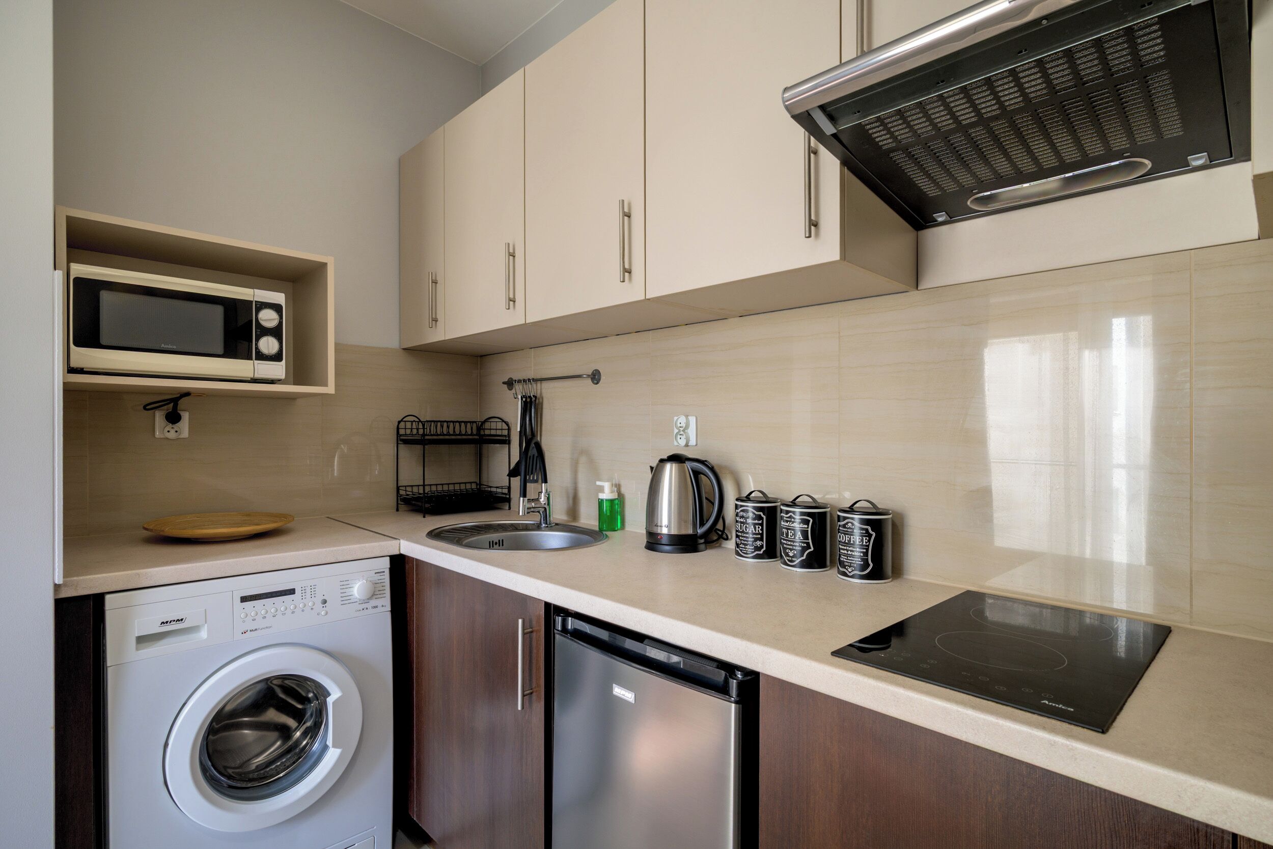 Una cocina compacta equipada con microondas, hervidor, cafetera y lavavajillas.
