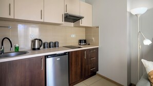 A modern kitchen with wooden cabinets, a stainless steel dishwasher, and a coffee maker. - RentPlanet - Studio Kościuszki (Wrocław)