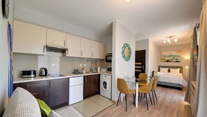 A compact apartment with a kitchenette, a dining area, a living room with a sofa, and a bedroom with a bed and a nightstand. - RentPlanet - Studio Kościuszki (Wrocław)