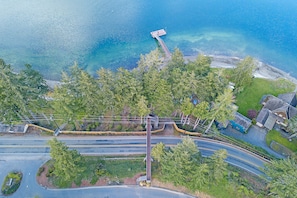 Luftaufnahme einer Küstenstraße mit einer Brücke, klarem blauen Wasser und umgebender Bepflanzung.