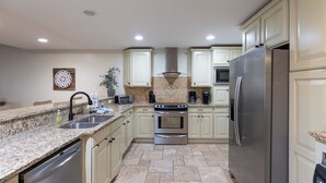 Una cocina con encimeras de granito, electrodomésticos de acero inoxidable y armarios de color claro.