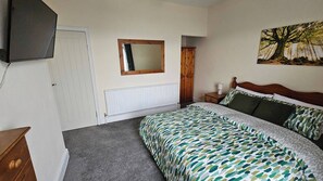 A bedroom with a bed, a dresser, a mirror, a radiator, and a painting on the wall. - Charming 3-bedroom Home in Doncaster, Perfect for Family, Friends & Contractors (Doncaster)