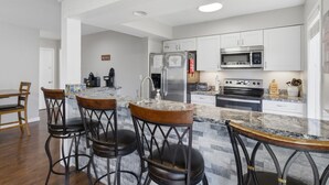 A modern kitchen with a central island, bar stools, stainless steel appliances, and white cabinetry. - Grand Ridge Retreat w Decks, TVs & Pool Access! (Osage Beach)