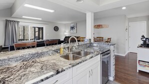 A modern kitchen with granite countertops, a stainless steel sink, and white cabinetry. - Grand Ridge Retreat w Decks, TVs & Pool Access! (Osage Beach)