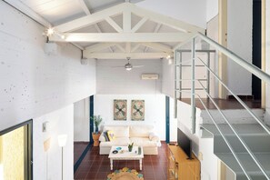 Un vaste espace de vie comprenant un canapé blanc, une table basse et un escalier.