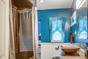 Un baño con un ventanal grande, un lavabo y una zona de ducha.