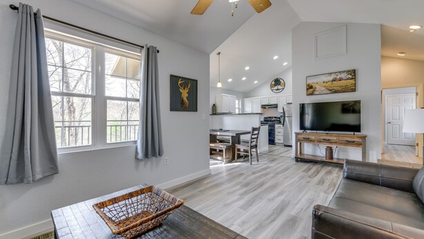 A spacious living area with a dining table, a sofa, a TV, and a ceiling fan. - Hot Tub Townhome Near Downtown Gatlinburg (Gatlinburg)