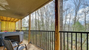 A wooden deck with a hot tub, chairs, and a view of a forest. - Hot Tub Townhome Near Downtown Gatlinburg (Gatlinburg)