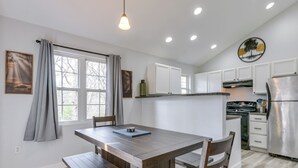 A kitchen with a wooden table, white cabinets, and a stainless steel refrigerator. - Hot Tub Townhome Near Downtown Gatlinburg (Gatlinburg)