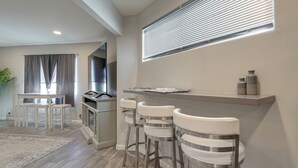 Eine moderne Küche mit Bar, Holzboden und Esstisch.