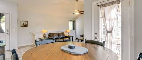 A round dining table with chairs, a ceiling fan, and a view of a deck through a door.