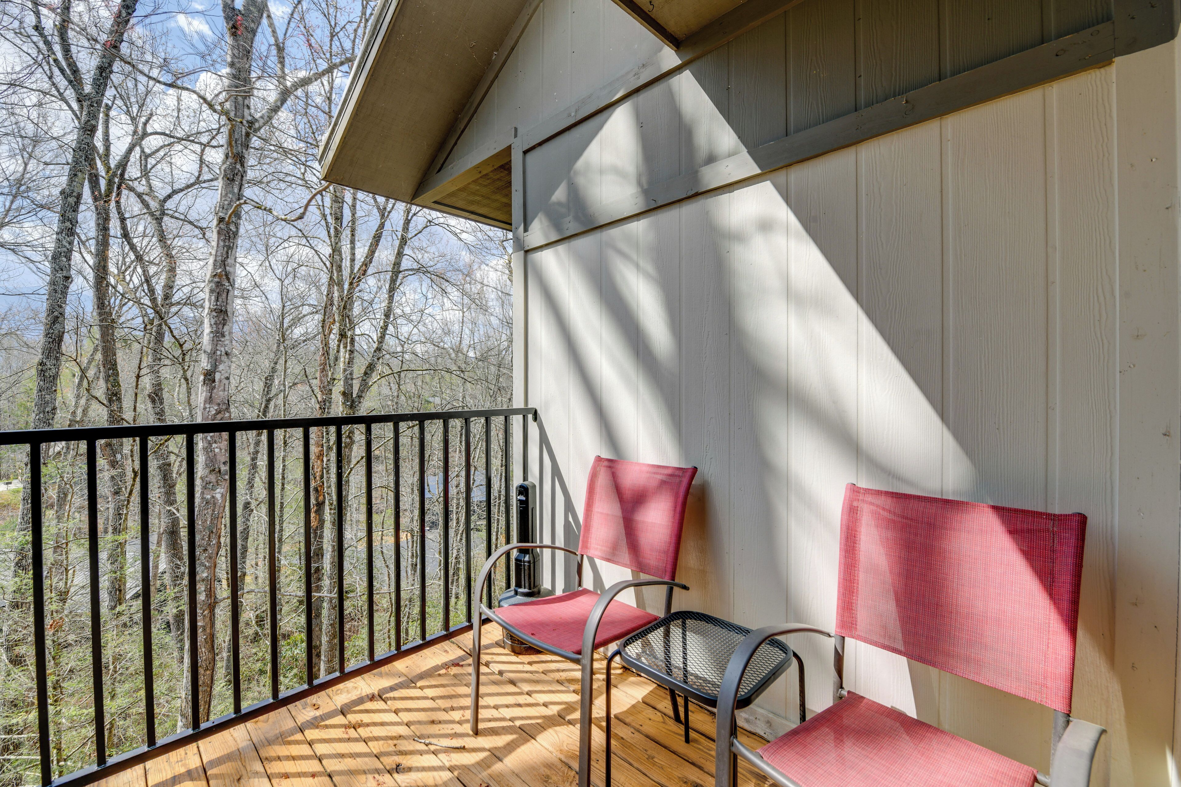 Un balcon doté d’un plancher en bois, de deux chaises et d’une rambarde en métal.