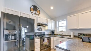Una cucina moderna con elettrodomestici in acciaio inossidabile, mobili bianchi e un piano di lavoro in granito.