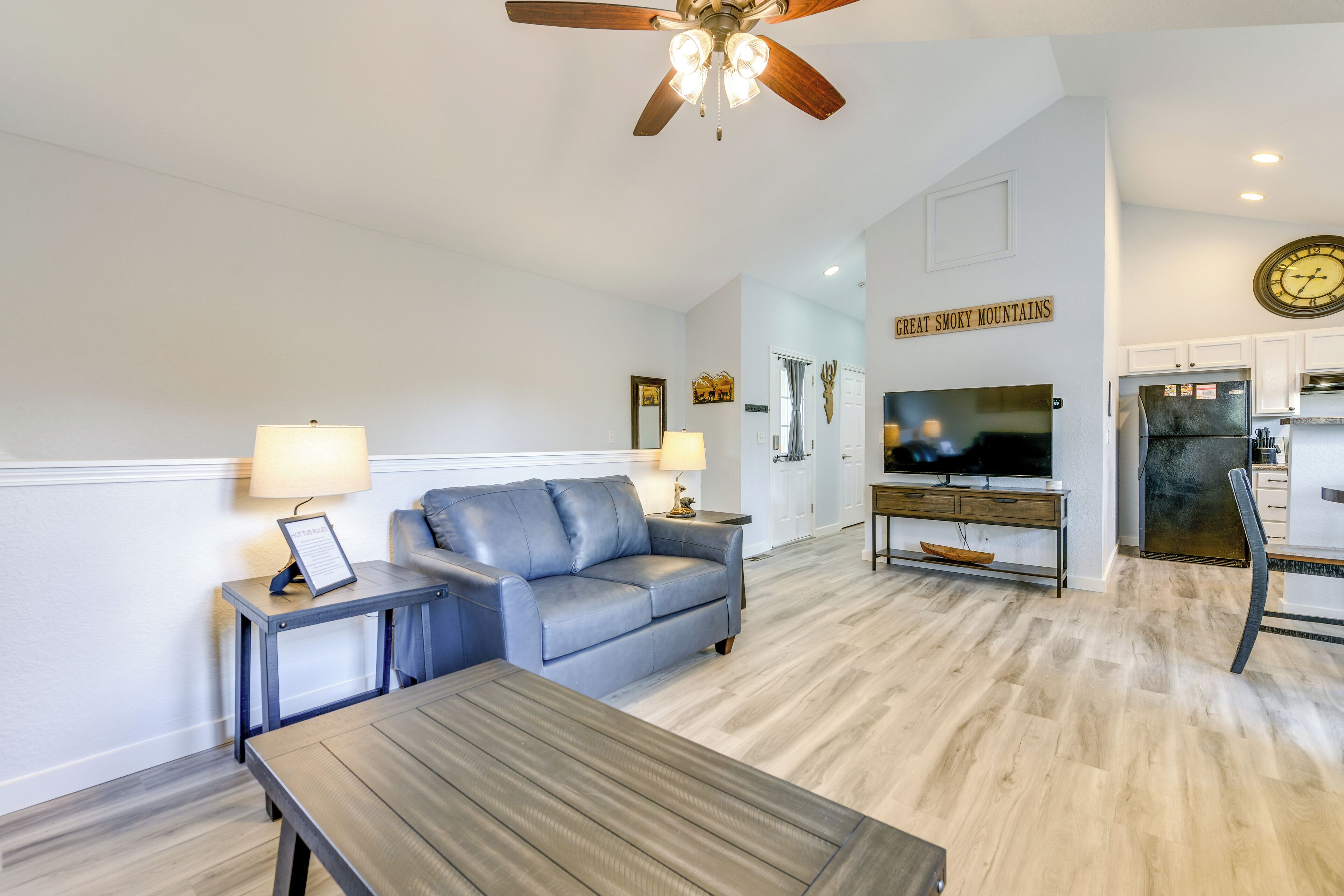 A living room with a sofa, coffee table, TV, and ceiling fan.